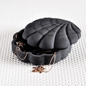 May include: A set of three ceramic mugs with a speckled, matte finish. The mugs are in shades of cream, light gray, and dark gray. Each mug has a simple, minimalist design, perfect for coffee or tea.