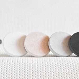 May include: Four round concrete knobs in white, beige, grey, and black.