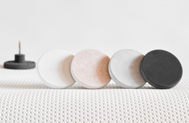 May include: Four round concrete knobs in white, beige, grey, and black.