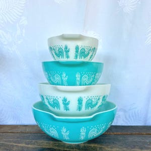May include: Set of four nesting mixing bowls with a white background and a turquoise blue rooster design. The bowls are stacked in order of size, with the largest bowl on the bottom and the smallest bowl on top.