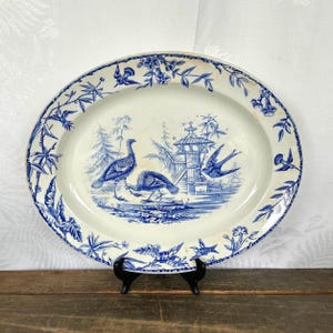 May include: A large oval blue and white porcelain serving platter with a blue and white floral border. The center of the platter features a blue and white illustration of two turkeys and a bird in front of a pagoda.
