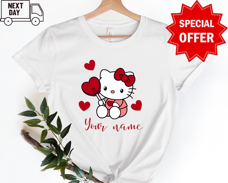 May include: White t-shirt with a cartoon image of Hello Kitty holding a red lollipop and surrounded by red hearts. The text "Your name" is printed below the image.