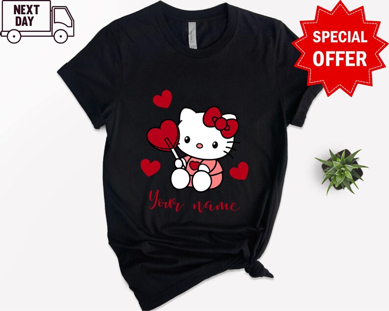 May include: Black t-shirt with a white Hello Kitty character holding a red heart lollipop. The character is surrounded by red hearts. The text "Your name" is printed below the character.