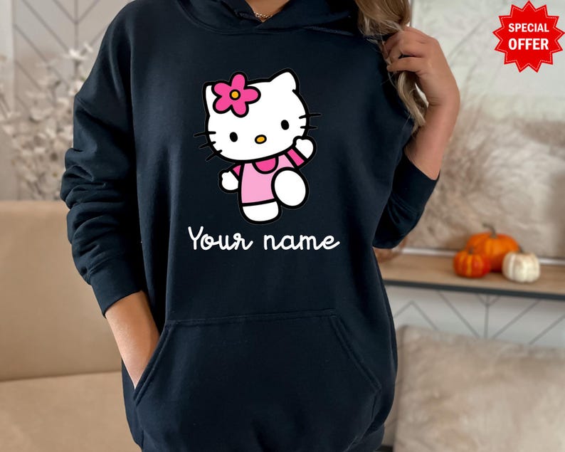 Puede incluir: Una sudadera con capucha negra con un personaje de dibujos animados con una flor rosa, que lleva un vestido rosa y saluda. El texto "Your name" est&aacute; impreso en blanco debajo. Una pegatina roja de "Special Offer" es visible.