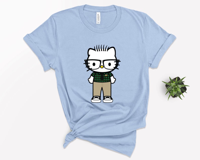 Puede incluir: Camiseta azul claro con una imagen de dibujos animados de Hello Kitty con gafas, una camisa de cuadros verdes y pantalones de color caqui.