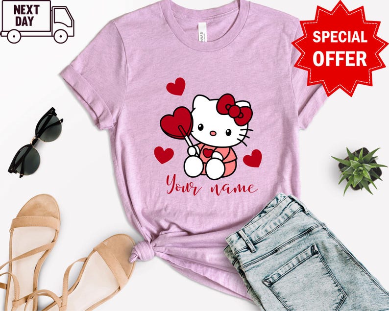 May include: Pink t-shirt with a cartoon image of Hello Kitty holding a red lollipop and surrounded by red hearts. The text "Your name" is printed below the image.