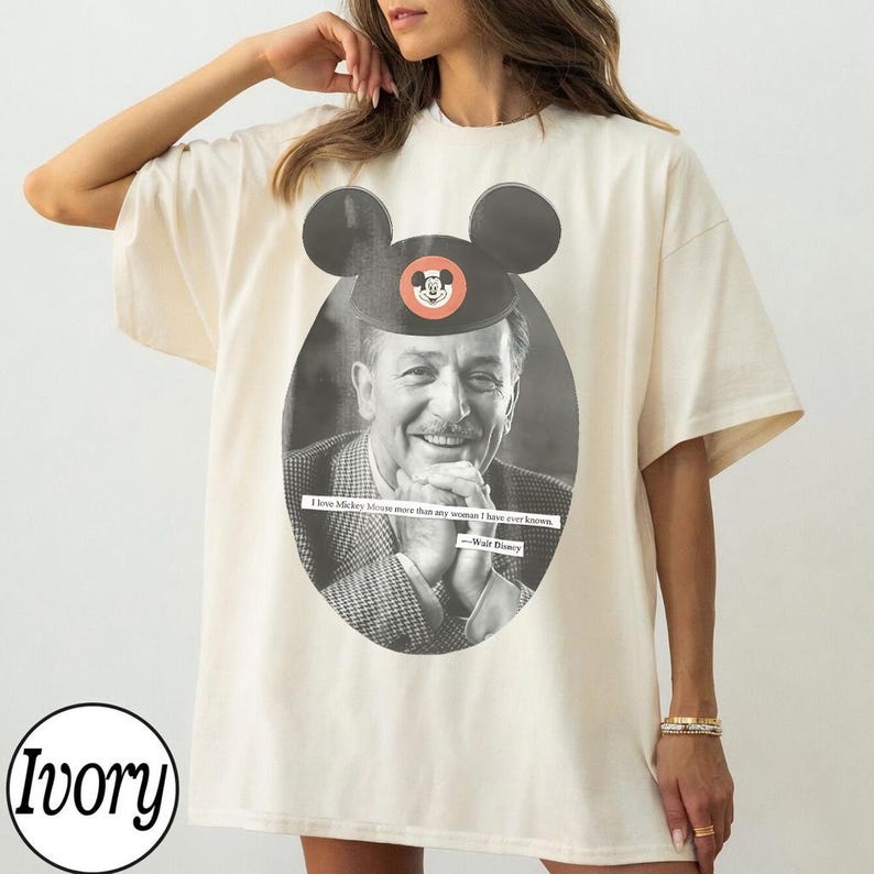 May include: Ivory-colored t-shirt featuring a black and white image of Walt Disney wearing a Mickey Mouse hat. The shirt includes the quote, "I love Mickey Mouse more than any woman I have ever known."