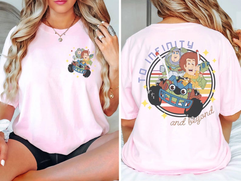 Op de afbeelding: Lichtroze T-shirt met een kleurrijke afbeelding van Toy Story-personages Woody, Buzz Lightyear en anderen in een speelgoedauto. De achterkant van het shirt heeft de tekst "To infinity and beyond" in een cirkel.