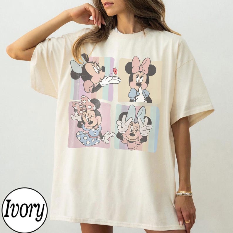 May include: Ivory-colored t-shirt featuring four panels with Minnie Mouse illustrations. Each panel showcases a different pose of Minnie Mouse, with pastel-colored striped backgrounds. The shirt has a relaxed fit and short sleeves.