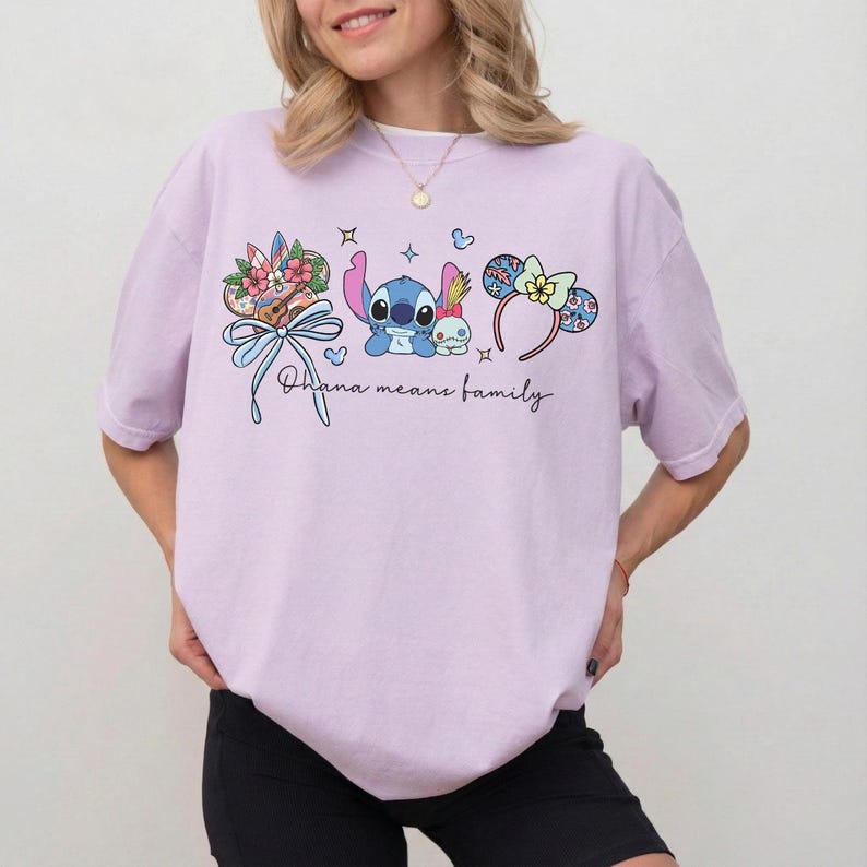 Puede incluir: Camiseta lila claro con un gr&aacute;fico colorido de Stitch, detalles florales y la frase "Ohana means family". El dise&ntilde;o incluye un lazo, estrellas y una diadema con detalles florales. La camiseta es de estilo c&oacute;modo e informal.