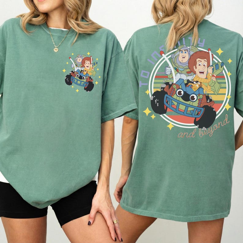 Op de afbeelding: Groen T-shirt met een Toy Story-afbeelding. De voorkant heeft een kleine afbeelding van personages in een auto, en de achterkant heeft een groter cirkelvormig ontwerp met de tekst "To infinity and beyond". Het shirt heeft korte mouwen.