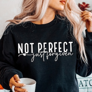 May include: Black sweatshirt with white text that reads "Not Perfect just forgiven" with a small heart symbol.