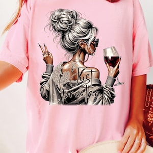 Peut inclure: T-shirt rose avec un motif graphique d'une femme tenant un verre de vin avec le texte "Just Breathe".