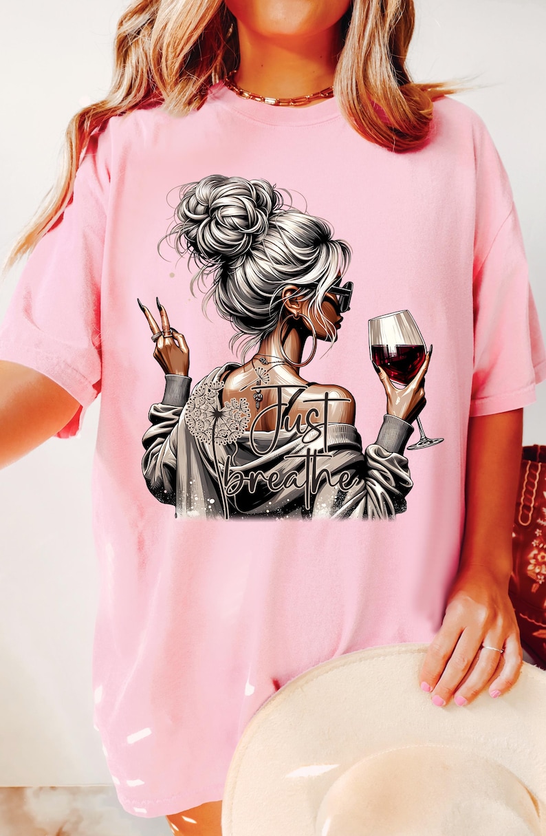 Peut inclure: T-shirt rose avec un motif graphique d'une femme tenant un verre de vin avec le texte "Just Breathe".