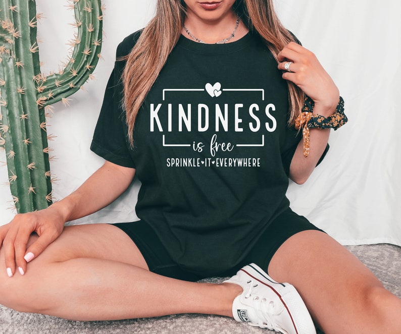 May include: A black t-shirt with white text that reads "KINDNESS is free - SPRINKLE IT EVERYWHERE" with a small heart graphic.