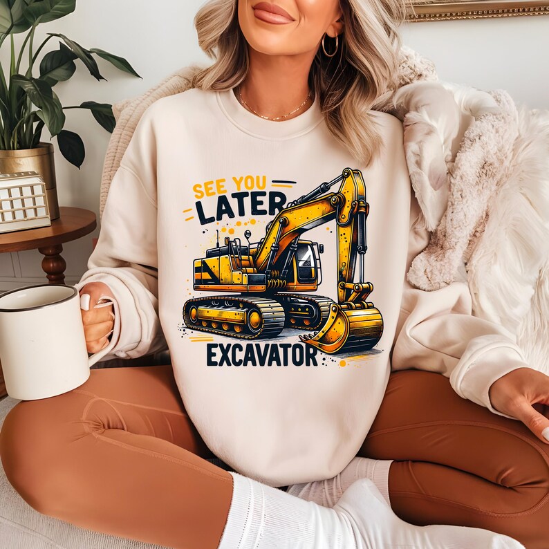May include: A cream-colored sweatshirt with a yellow excavator graphic and the text "See You Later Excavator".