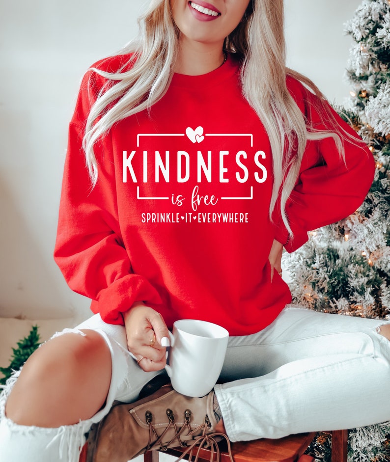 May include: Red sweatshirt with white text that reads "KINDNESS is free SPRINKLE IT EVERYWHERE" with a small heart graphic.