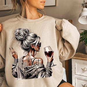 Peut inclure: Un sweat-shirt beige avec un motif repr&eacute;sentant une femme tenant un verre de vin rouge et le texte "Just Breathe".
