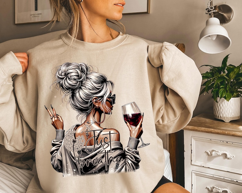 Peut inclure: Un sweat-shirt beige avec un motif repr&eacute;sentant une femme tenant un verre de vin rouge et le texte "Just Breathe".