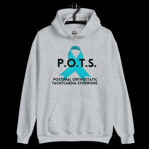 Pode incluir: Um moletom cinza claro com um bolso frontal e um capuz. A frente do moletom apresenta o texto "P.O.T.S." acima de uma fita azul-turquesa, com as palavras "POSTURAL ORTHOSTATIC TACHYCARDIA SYNDROME" abaixo.