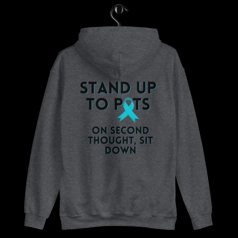 Pode incluir: Moletom cinza escuro com o texto "STAND UP TO POTS" acima de uma fita azul-turquesa e o texto "ON SECOND THOUGHT, SIT DOWN". O moletom est&aacute; pendurado em um cabide preto.