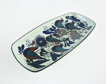 May include: A white ceramic serving dish with a black rim. The dish is decorated with a colorful floral pattern and birds in shades of blue, green, red, and brown.