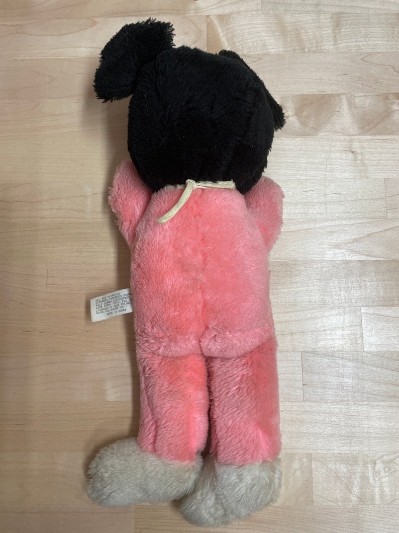 Peut inclure: Jouet en peluche rose avec des cheveux noirs en queue de cheval. Le jouet porte un pyjama rose avec des pieds blancs. Le jouet a une &eacute;tiquette qui indique "Tous nouveaux mat&eacute;riaux. Ext&eacute;rieur : 100 % polyester. Remplissage : 100 % polyester. Entretien : Lavage en surface uniquement. Fabriqu&eacute; en Chine."