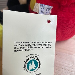 May include: A white tag with black text that reads "This item meets or exceeds all Federal and State safety regulations, including U.S. Dept. of Commerce toy safety standard PS 72-76. Designed and made for Walt Disney World. WALT DISNEY PRODUCTIONS. Product of Taiwan."
