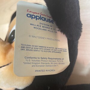 May include: A plush toy with a black ear and a tag that reads "Everyone loves to get applause." The tag also includes the text "WALT DISNEY PRODUCTIONS" and "PRINTED IN KOREA."