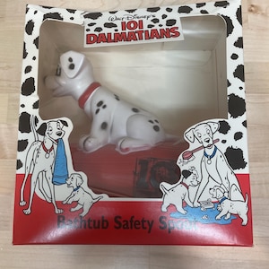 May include: A white and black spotted Dalmatian figurine with a red collar sits inside a box. The box features the text "Walt Disney's 101 Dalmatians" and illustrations of Dalmatian dogs. The box has a red base with the text "Bathtub Safety Spot".