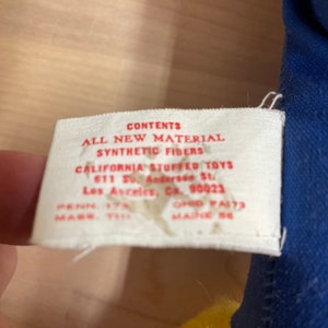 May include: A white tag with red text that reads "CONTENTS ALL NEW MATERIAL SYNTHETIC FIBERS CALIFORNIA STUFFED TOYS 611 So. Andersen St. Los Angeles, Ca. 90023 PENN. 17N OHIO FA173 MADE IN 58"
