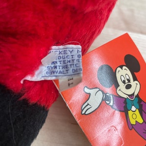 May include: Red and black plush Mickey Mouse toy with a tag that reads "Mickey Mouse Product of All Contents Synthetic Fibre Walt Disney Productions."