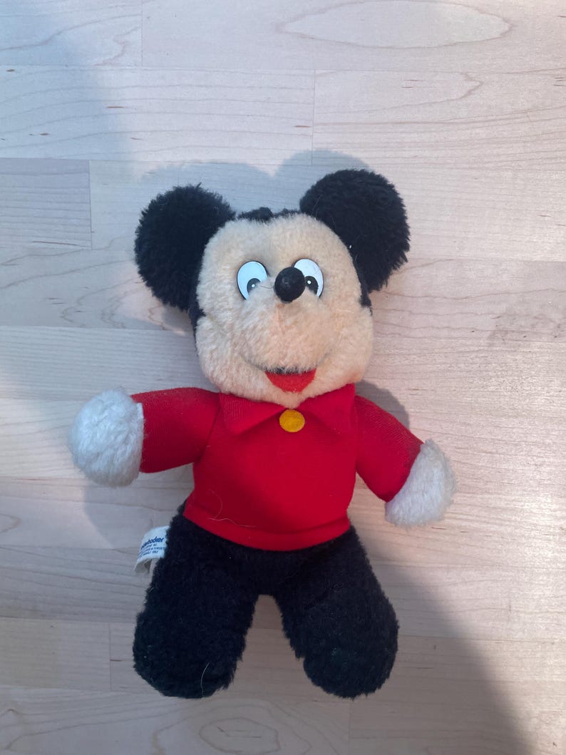 Puede incluir: Un peluche vintage de Mickey Mouse. El peluche presenta una camisa roja con un bot&oacute;n amarillo, pantalones negros y guantes blancos. La cara de Mickey es de color crema con orejas negras y una nariz negra. Un cl&aacute;sico de Disney.