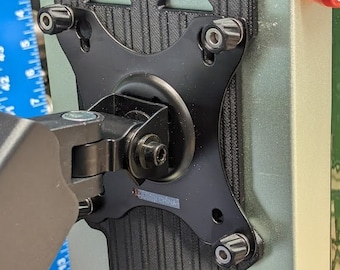 May include: A black 3D printed bracket with a fan and a round, black, adjustable arm attached to it. The bracket is mounted on a light green box with a power cord and USB port.