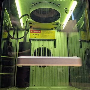 May include: A green laser engraving machine with a warning sign that reads "Danger Class 4 Laser - Avoid eye or skin exposure to direct or scattered radiation".