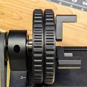 K&ouml;nnte beinhalten: Nahaufnahme eines schwarzen 3D-Druckers mit zwei schwarzen Zahnr&auml;dern und einem schwarzen Arm. Der Drucker hat ein Etikett mit der Aufschrift "XTOOL" und "C-."