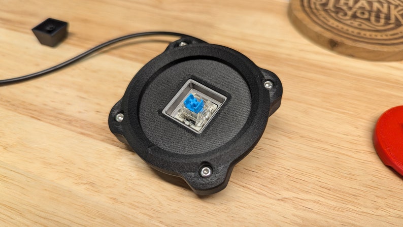 Op de afbeelding: Een zwarte ronde mechanische toetsenbord-toetsdop met een blauwe toetsdop en een transparante schakelaar.