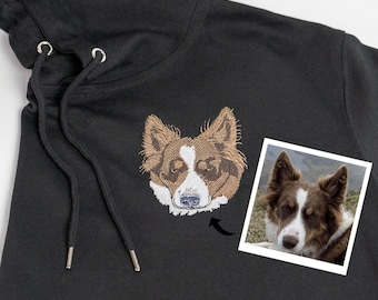 May include: A black hoodie with an embroidered image of a brown and white dog's face. The dog is a Border Collie.