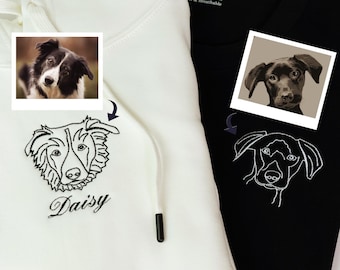 Op de afbeelding: Een witte hoodie met een zwart-witte hond geborduurd op de voorkant. De naam van de hond, Daisy, is geborduurd onder de afbeelding. Een foto van de hond is te zien boven de borduurwerk. De hoodie ligt naast een zwarte hoodie met een vergelijkbare borduurwerk van een zwarte hond.