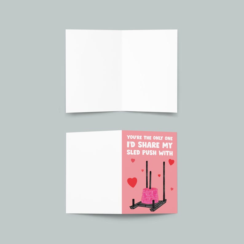 Pu&ograve; includere: Un biglietto di San Valentino rosa e bianco con il testo "You're the only one I'd share my sled push with". Il biglietto presenta un'illustrazione di un peso per slitta con cuori.