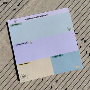 May include: A light blue, purple, and yellow brain dump notepad with the text "Brain dump: handle with care" at the top. The notepad is divided into four sections: "Genius ideas", "Probably important", "Random nonsense", and "Doodle zone".