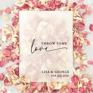 May include: A rectangular card with the words "THROW SOME love" in black script, surrounded by pink and peach flower petals. The names "LISA & GEORGE" and the date "25th July 2026" are printed below the text.