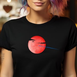 May include: A woman with blue and purple hair is wearing a black t-shirt with a red circle and a blue line graphic. She is standing in front of a blurred background of lights.
