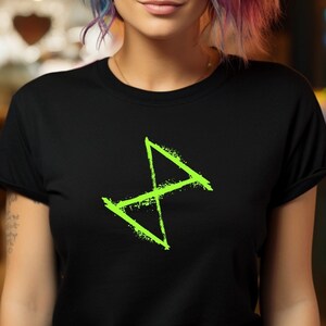 May include: A woman with blue and pink hair is wearing a black t-shirt with a green symbol on it. The symbol is a stylized X with a diagonal line through it.