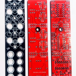 Może przedstawiać: Trzy elektroniczne płytki drukowane. Czarna płytka z białymi okrągłymi wycięciami i tekstem "333 OFF ATT IN OUT ATTEO". Dwie czerwone płytki z elementami elektronicznymi i tekstem. Jedna płytka ma tekst "333-ATTEO TH U2 Control Pcb".
