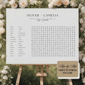 May include: A white wedding sign with a black word search puzzle featuring wedding-related words like "bride", "groom", "rings", "love", "ceremony", "reception", "dance", "flowers", "music", "toast", and "venue". The sign also includes the names "Oliver + Camelia" and the text "Sup & Search".
