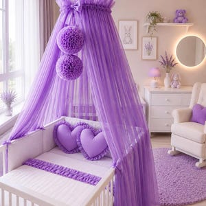 May include: A baby crib with a canopy of sheer purple fabric. The crib is decorated with heart-shaped pillows and a matching rug. The room is decorated in shades of purple and white, creating a soft and inviting nursery.