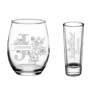 Op de afbeelding: Een set van twee heldere glazen drinkglazen met een bloemenmotief en de naam "Jasmine" erop gegraveerd.