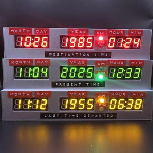 May include: A three-tiered digital time display unit featuring red, green, and yellow LED readouts. Each tier is labeled with Month, Day, Year, Hour, and Min, with text plates reading Destination Time, Present Time, and Last Time Departed.