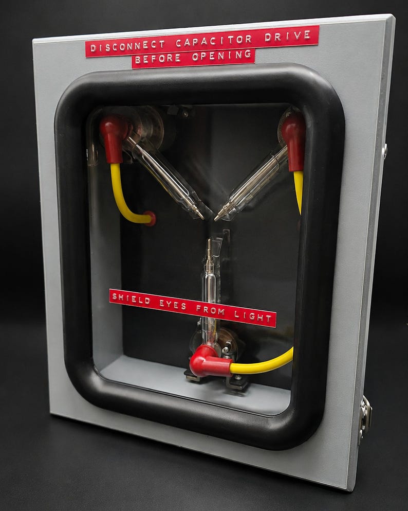 Three-quarter view of the Flux Capacitor showing the metal case, clear window and warning labels